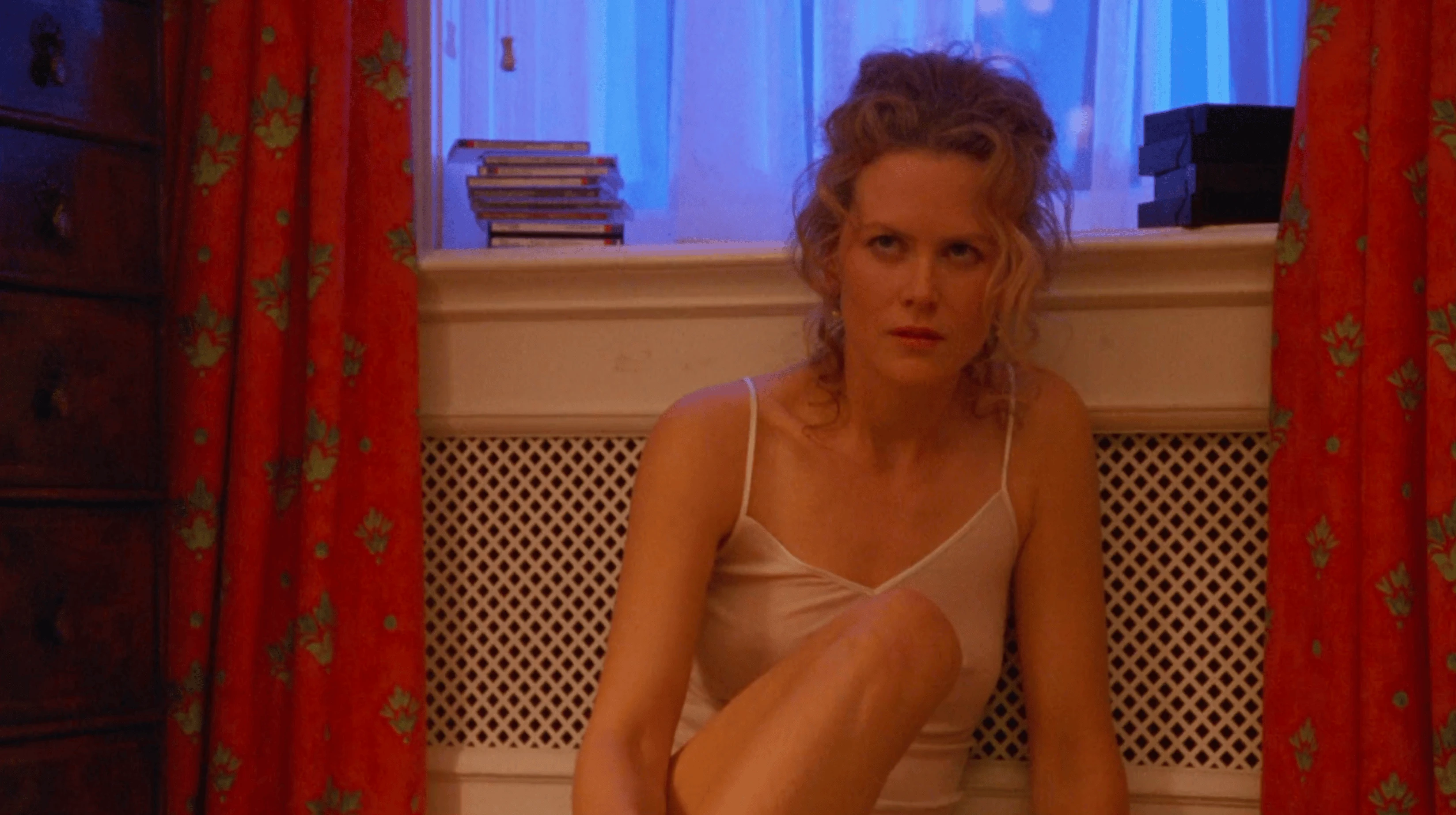 Alice assise seule près de la fenêtre, rideaux rouges